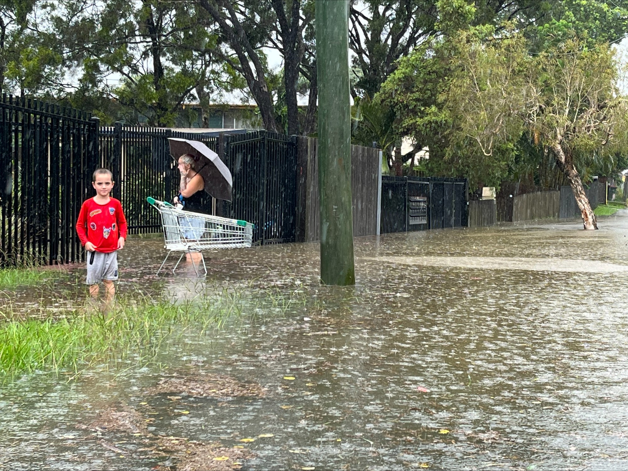 a young boy and woman stand in flood waters