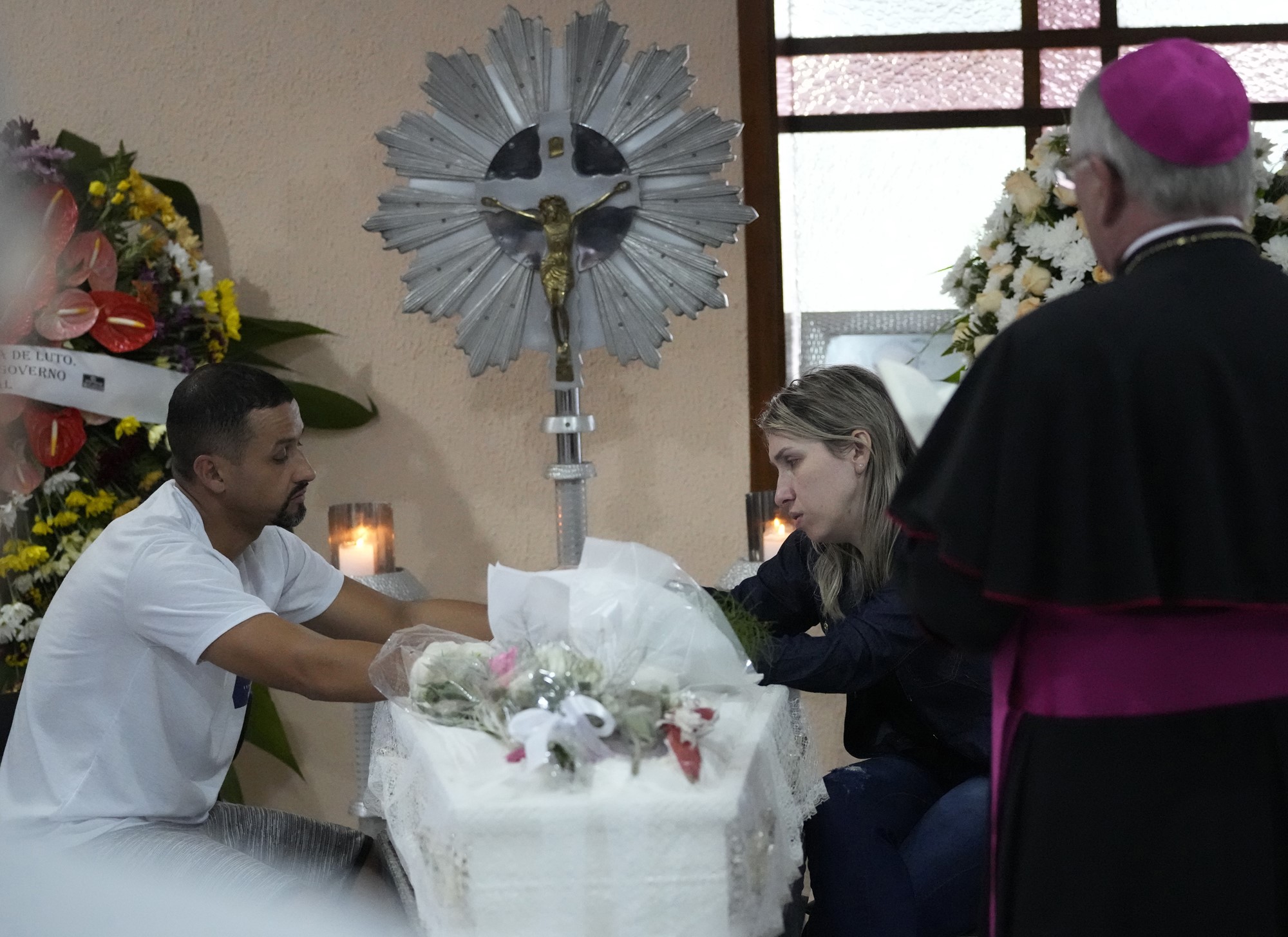 Parents sit alongside the coffin that contain the remains of their seven-year-old Larissa Maia Toldo.