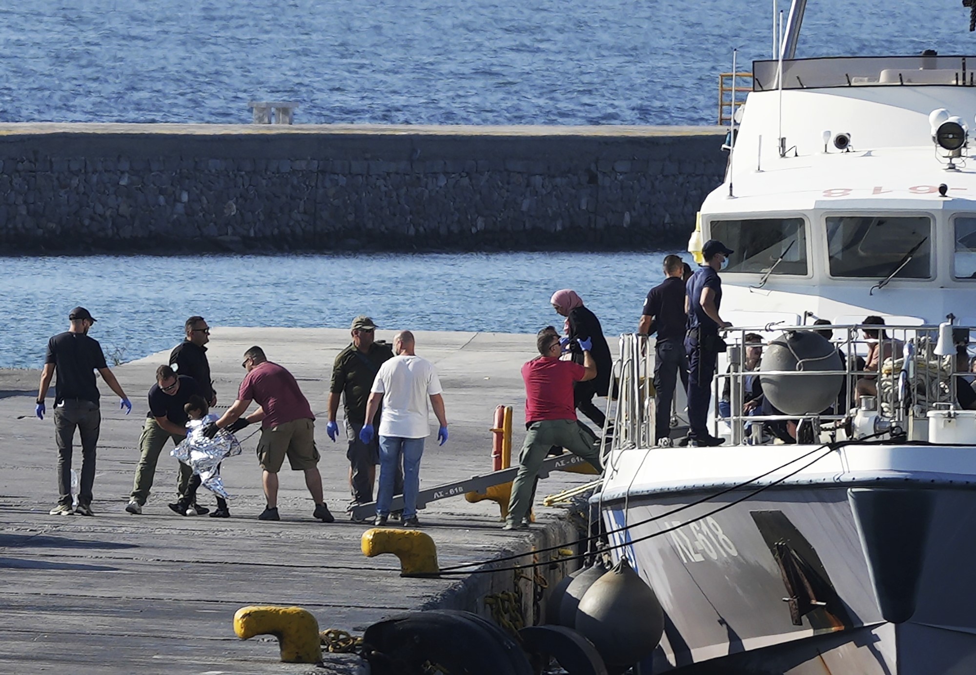 A child escorted by coast guard officers disembarks with other migrants from a vessel after a rescue operation