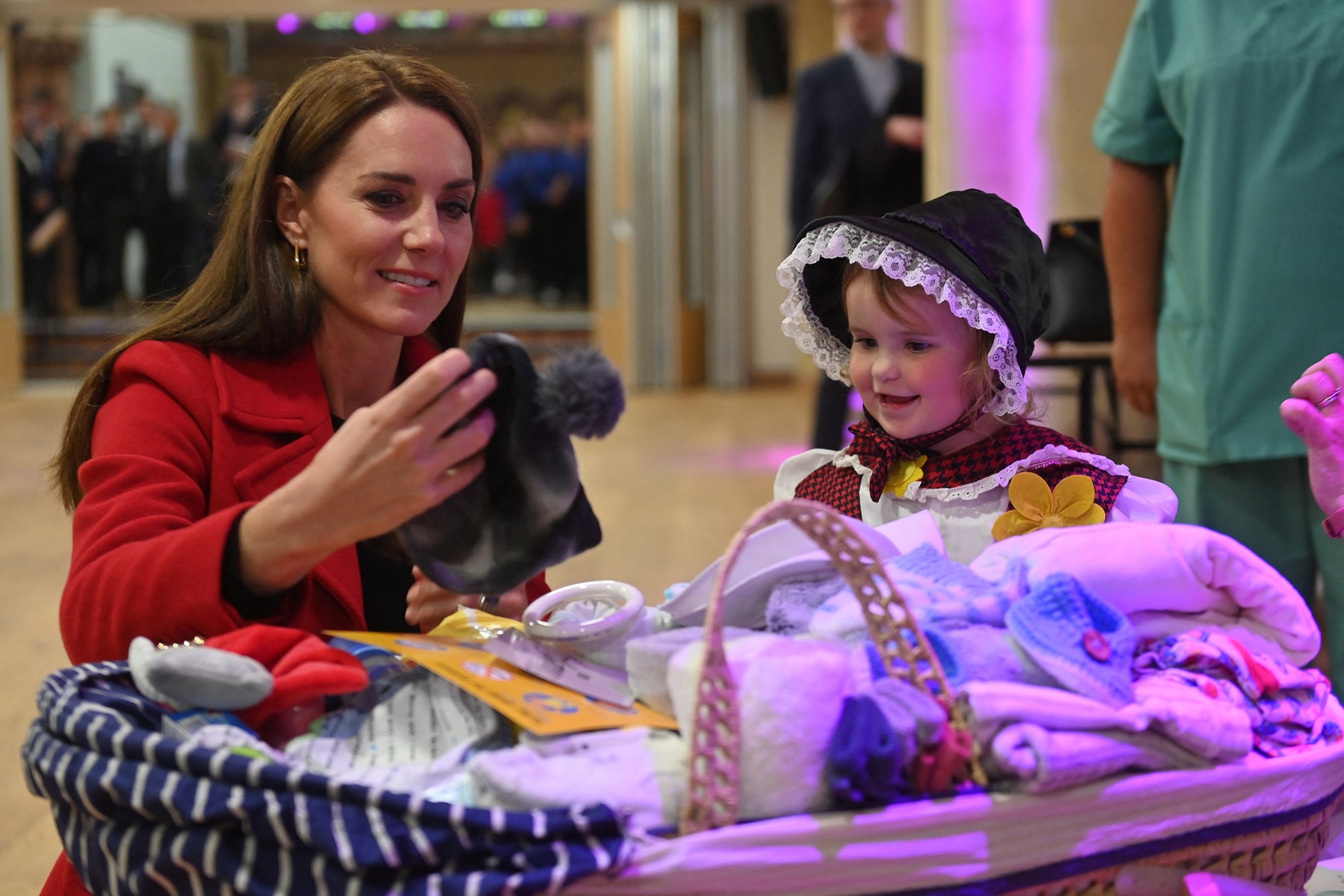 Princess Catherine looks at a hat next to a young girl