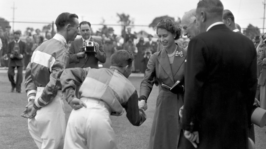 A young Queen Elizabeth shakes the hand of a jockey