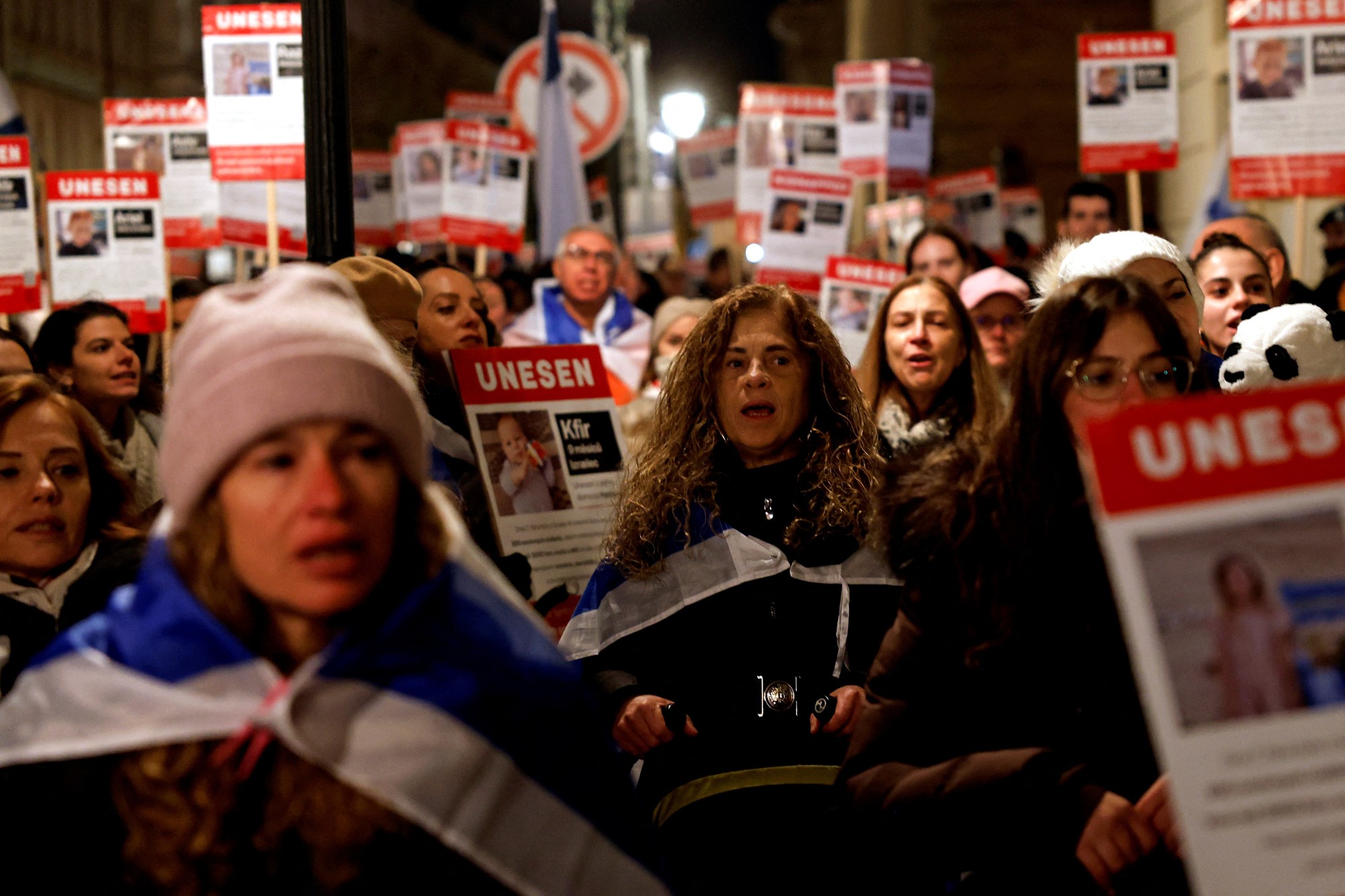 a group of women chant and hold signs in the dark and cold