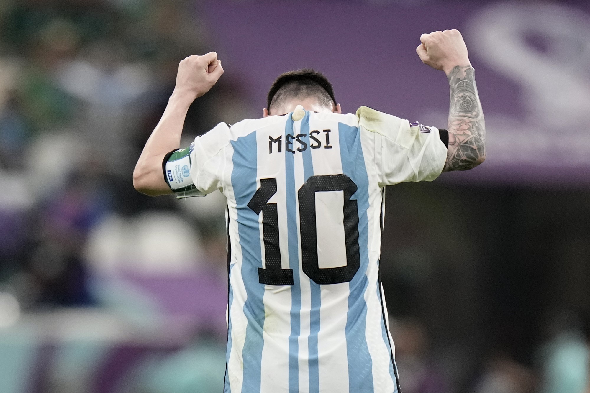 Argentina's Lionel Messi puts his head down and his fists up in celebration in this photo taken from behind showing his Messi, number 10 shirt.