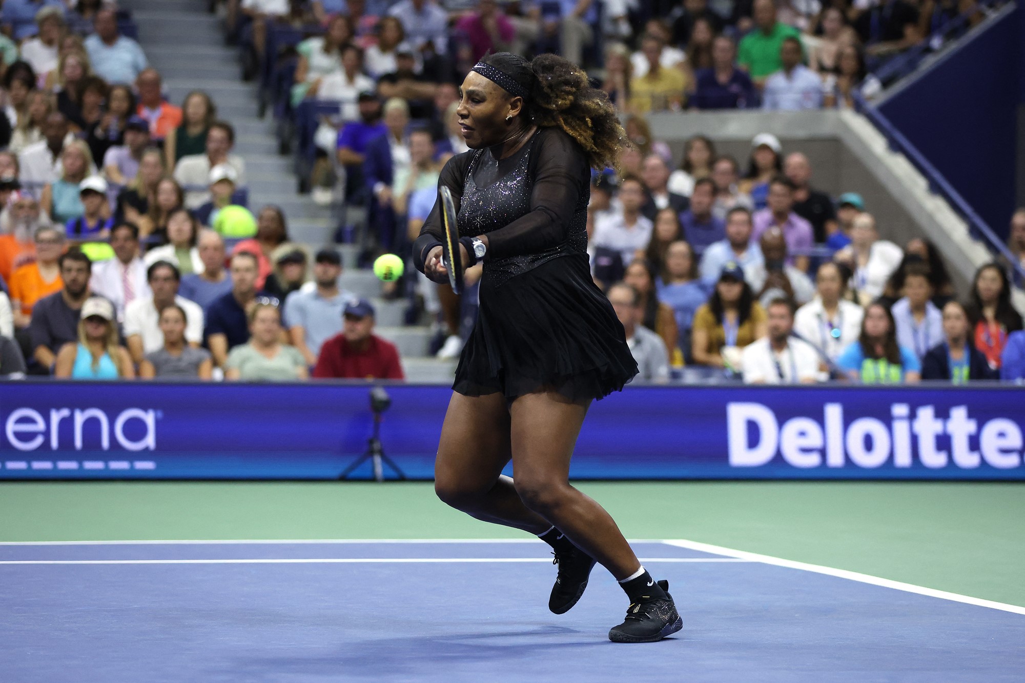 A woman in all black plays tennis.