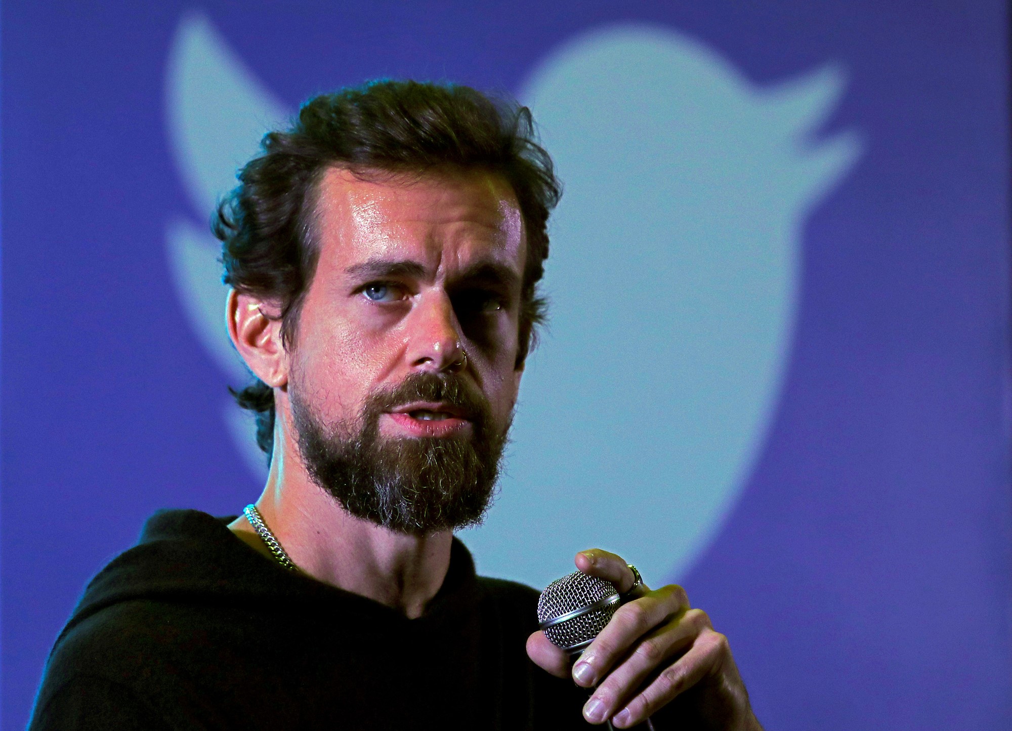 Jack Dorsey stands in front of a Twitter logo