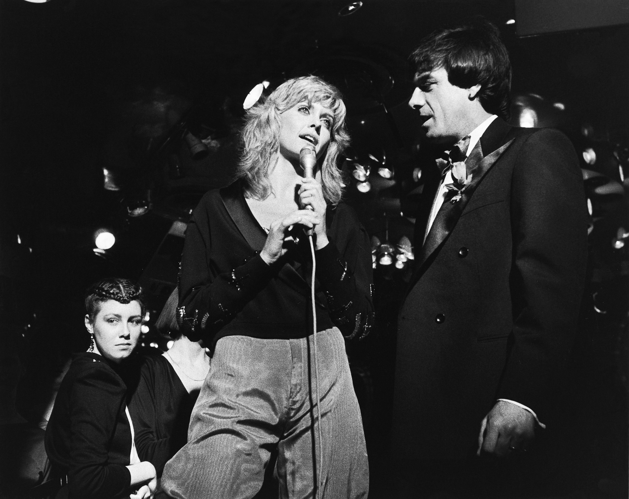 A black and white photo shows Olivia Newton-John and Molly Meldrum performing together.