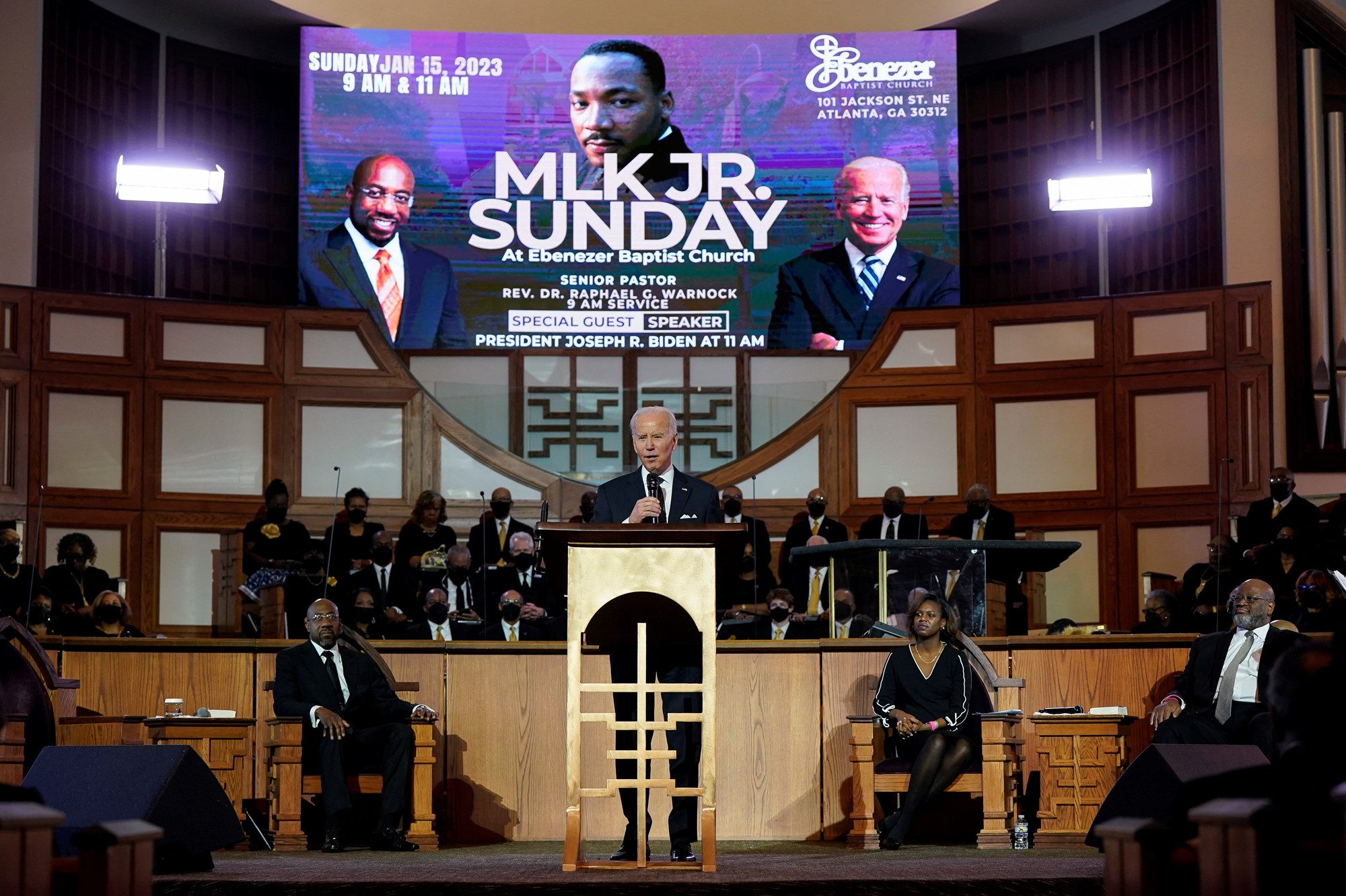 Biden habla en una iglesia con una pantalla de plasma encima de él leyendo el domingo de Martin Luther King Jr.