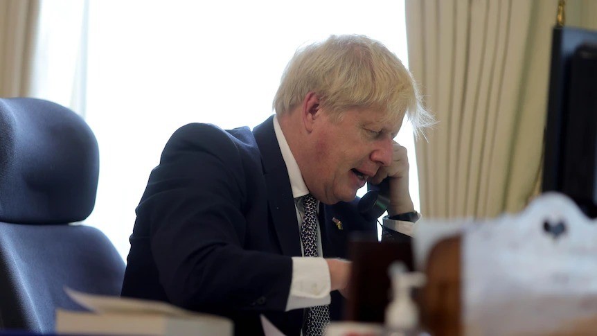 Boris Johnson sits in his office and talks on the phone.