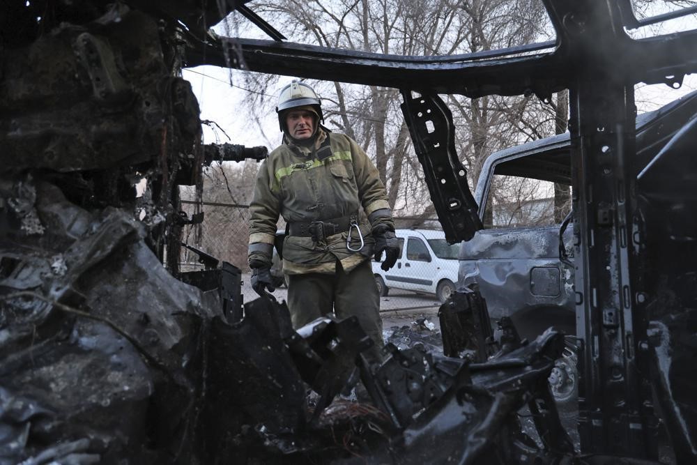 A firefighter examines a burnt out car.