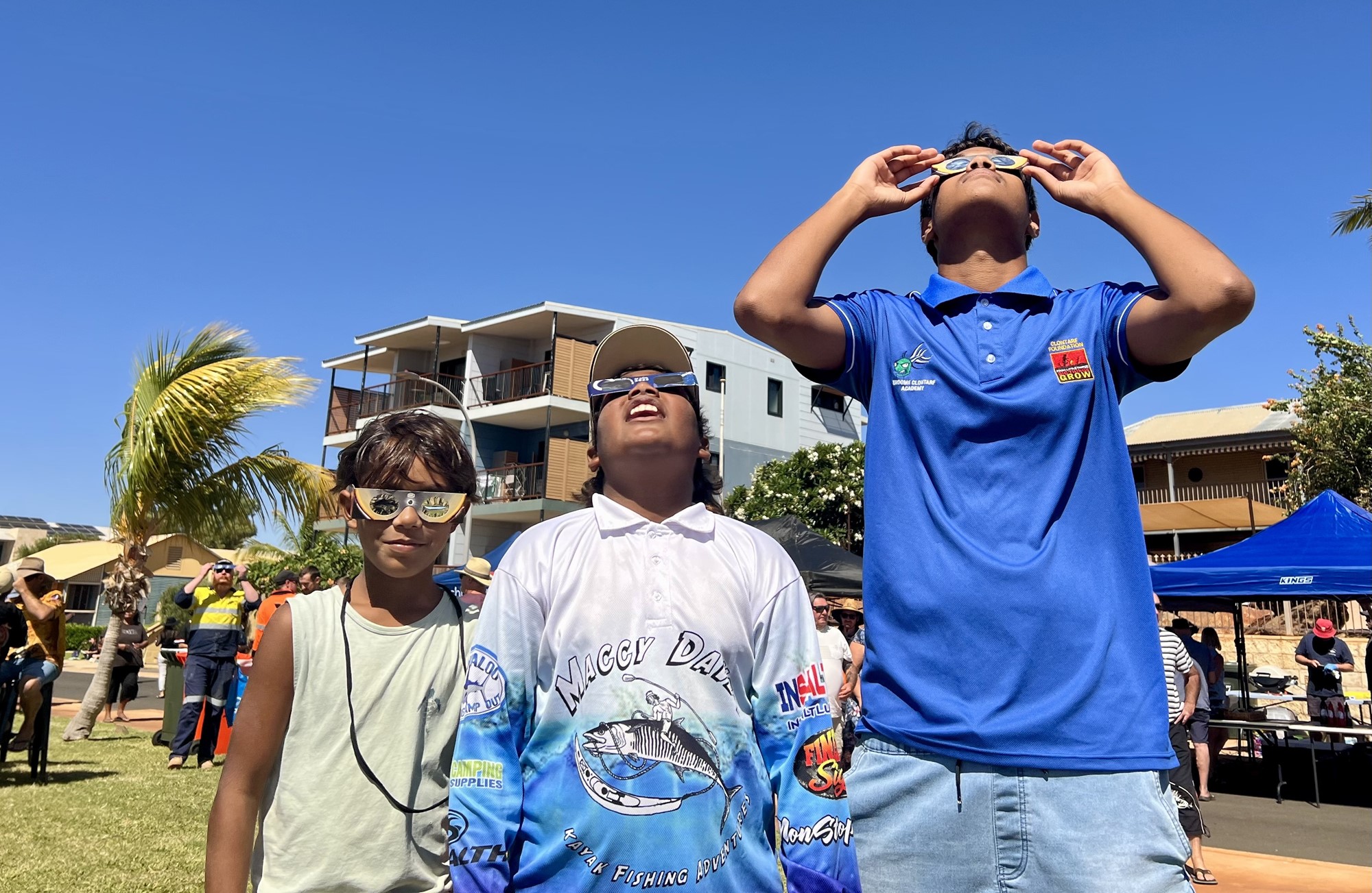 Three young boys with solar glasses look up in Onslow.