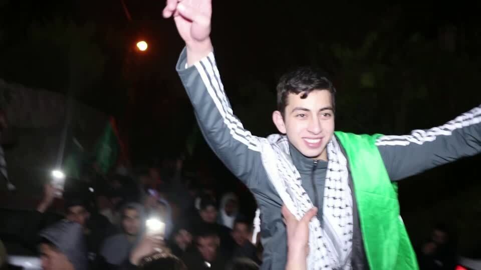 A boy draped in Palestinian flag is lifted up as he celebrates