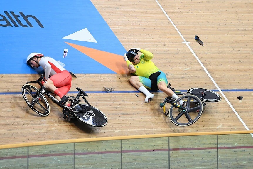 Two cyclists lie on the Commonwealth Games track after a crash.