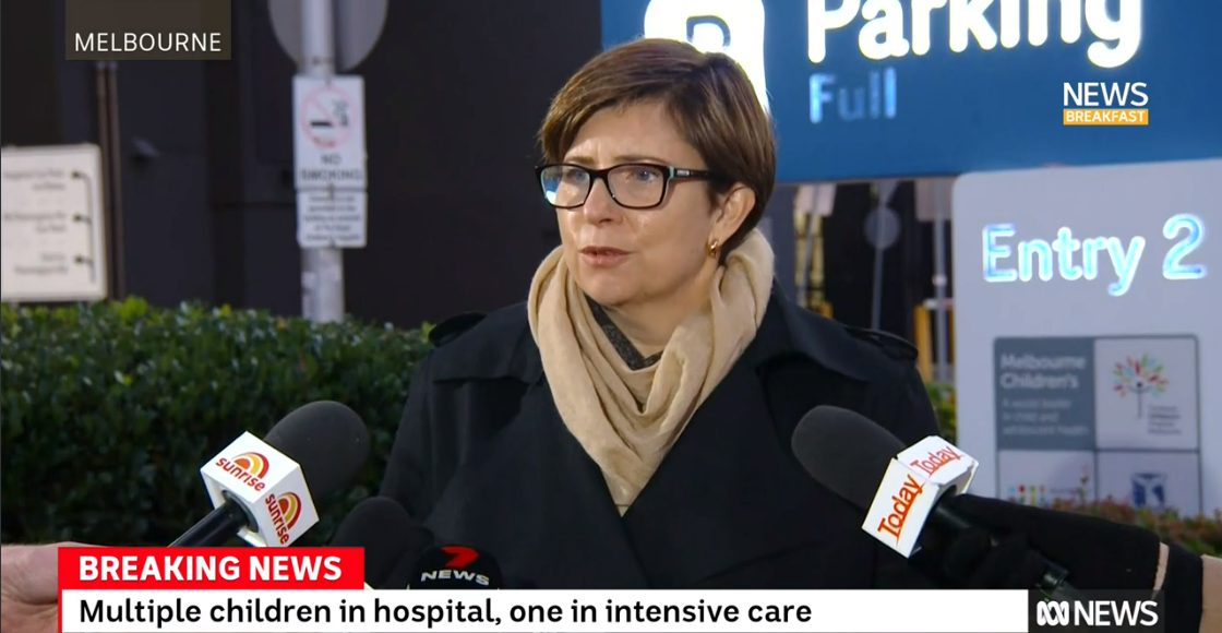 A woman in a glasses and scarf gives a press conference outside a hospital