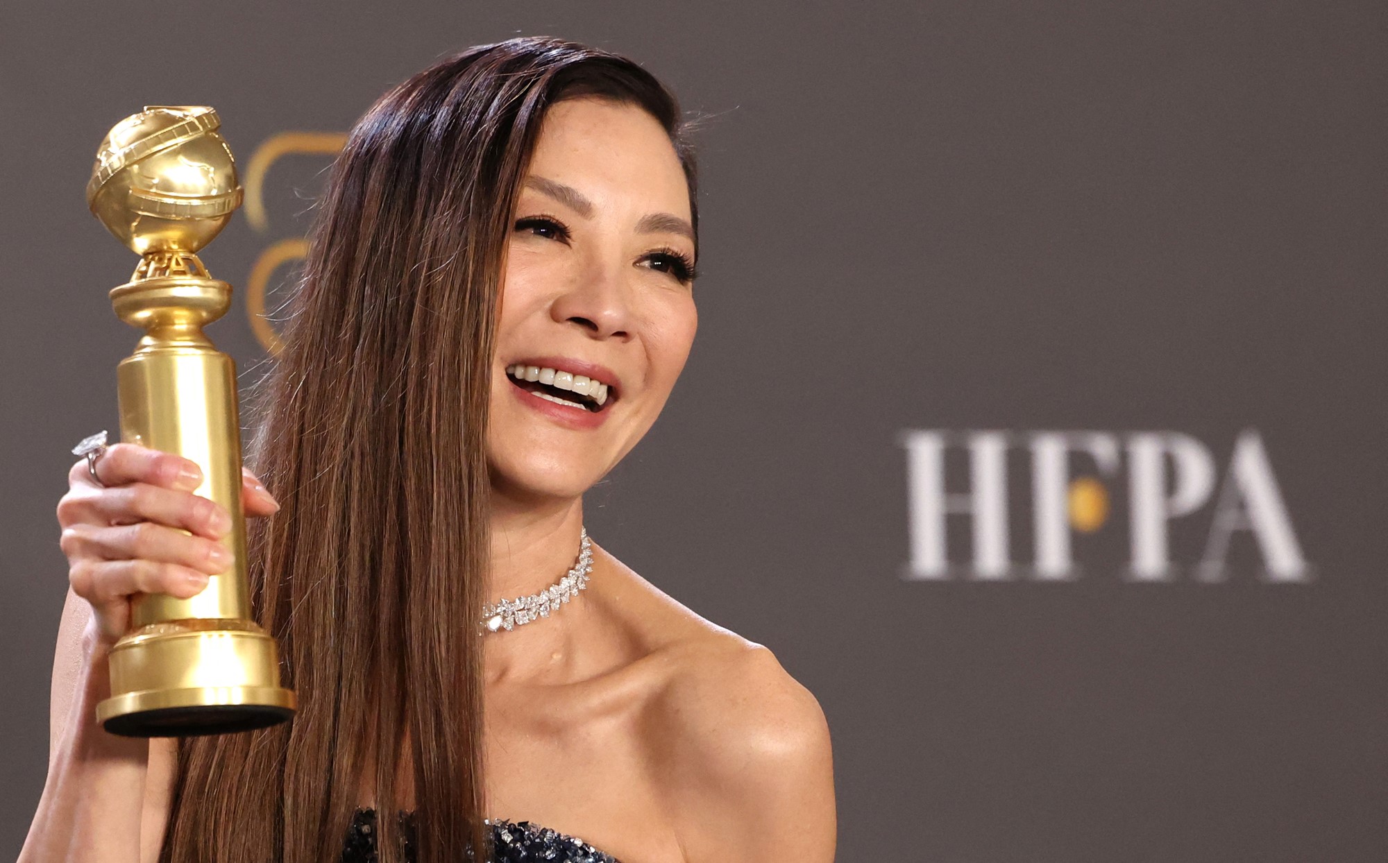 Michelle Yeoh holds up her Golden Globe