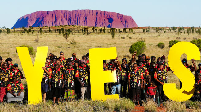 A group of people hold up a sign that says 'yes'