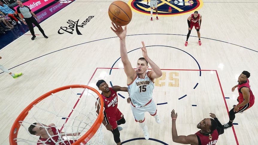A top-down photo of a white basketballer shoots a layup  near other opposing players