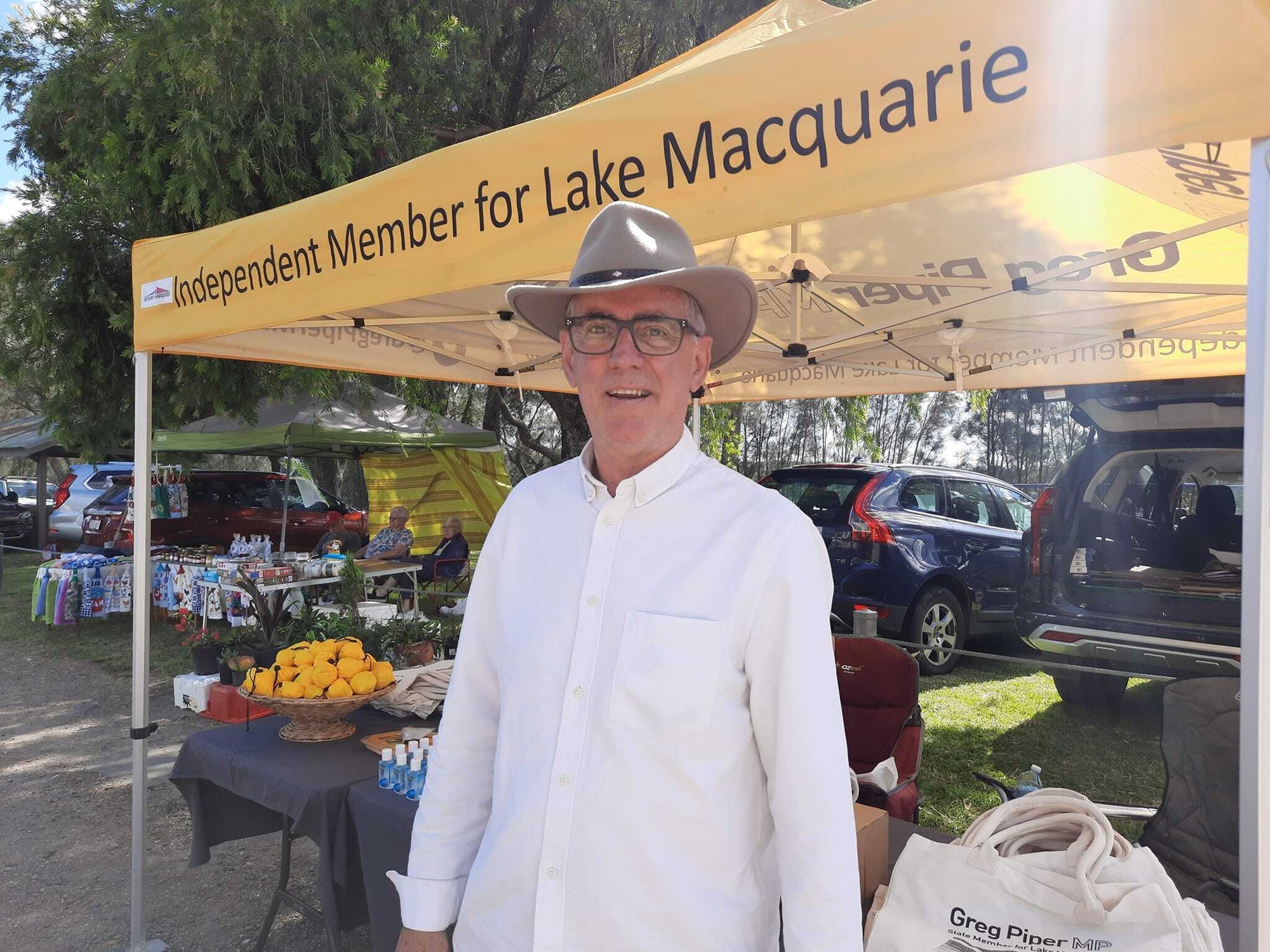 A man with a hat stands at an outdoor stall