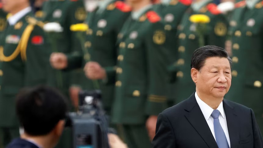 Xi Jinping walks in front of a row of uniformed military members