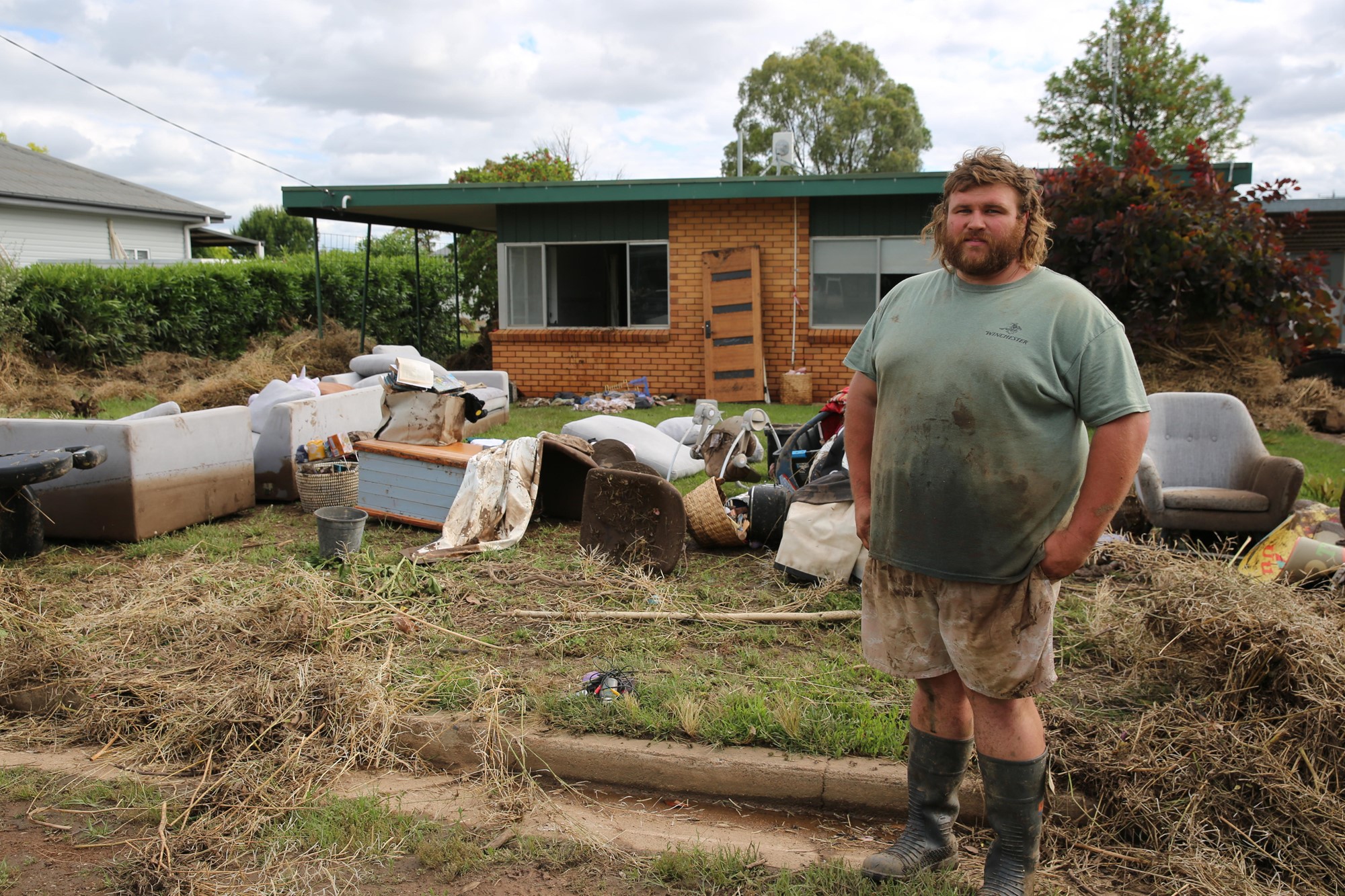 Blake stands outside his home with his ruined furniture strewn across the front lawn.