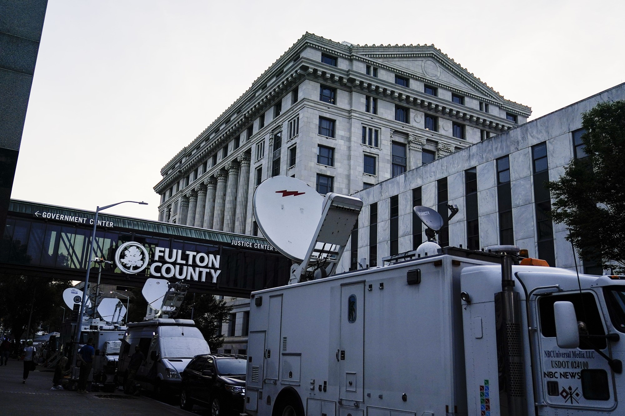 TV broadcast trucks lined up outside a large courthouse building