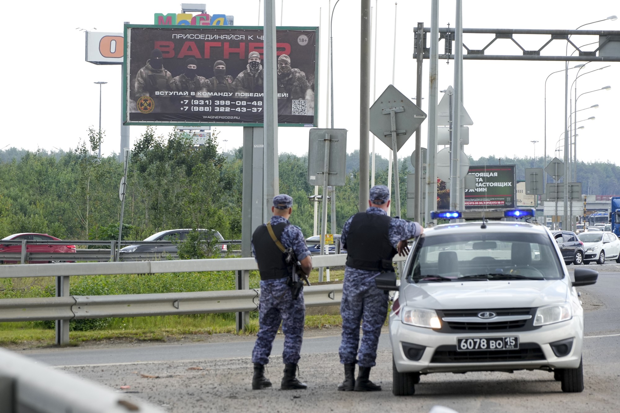 Policemen guard an area in front of a billboard reading "Join us at Wagner."