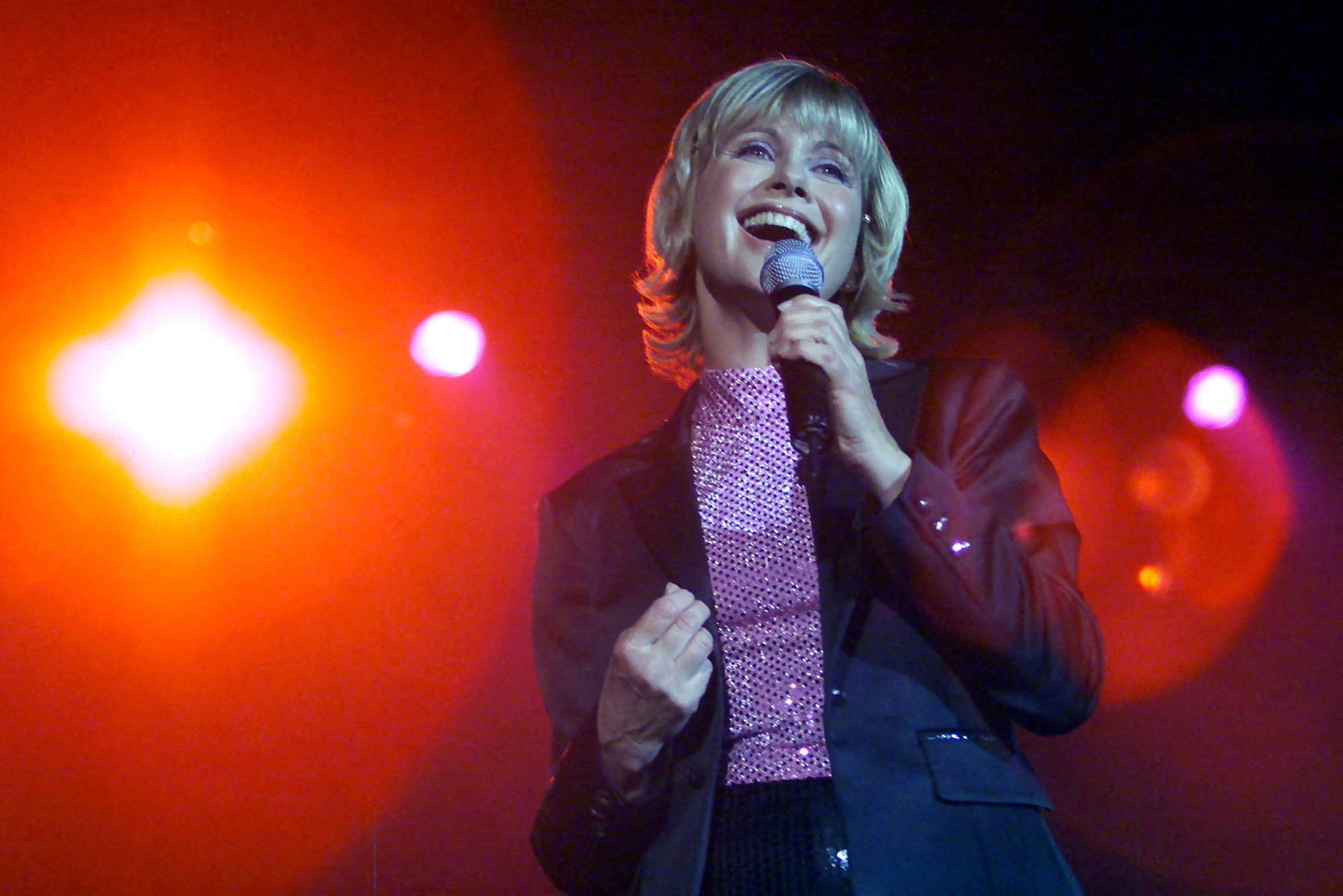 A woman with a blonde bob sings into the microphone.