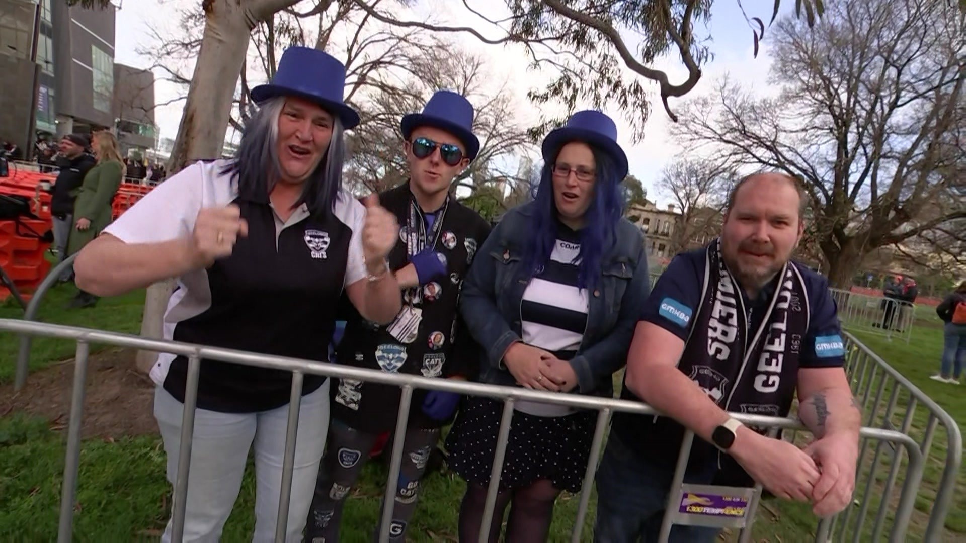 Four Geelong supporters, dressed in blue and white, pump their fists.