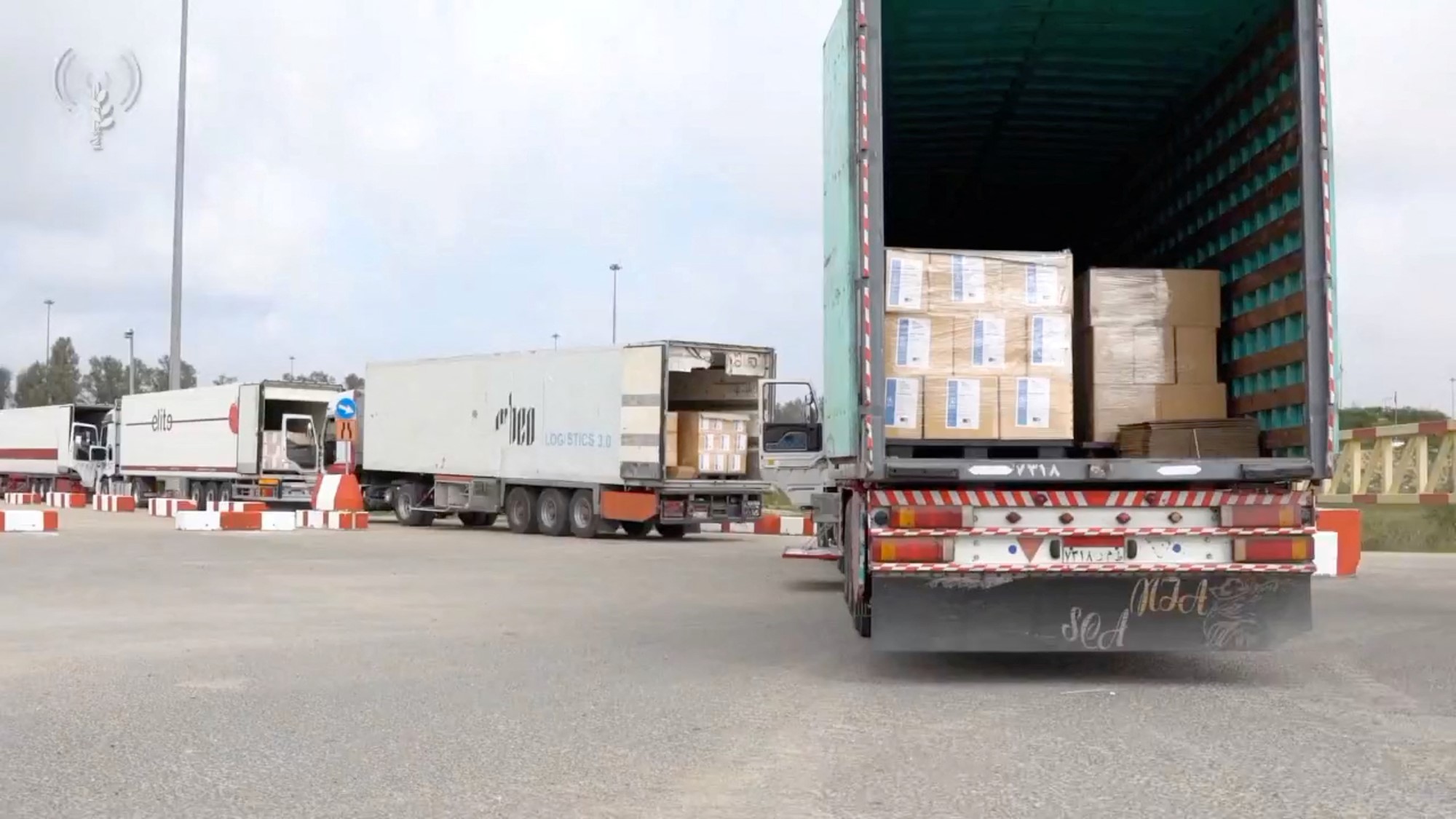 A convoy of trucks with their backs open revealing cardboard boxes. 