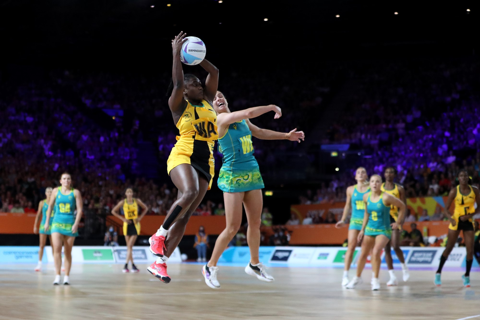 An Australian netball player and a Jamaican player jump for the ball in the Commonwealth Games gold medal match.