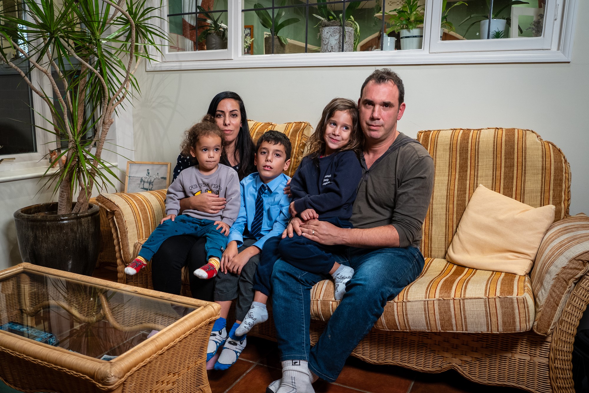 A couple with three children sit on a couch 