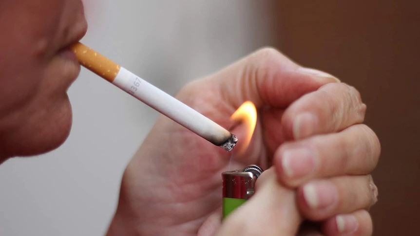 A close up of someone lighting a cigarette with a small lighter