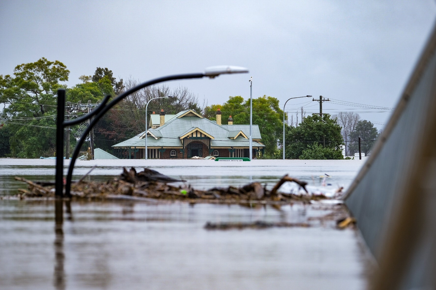 a lamp post submerged in floodwaters surrounded by debris