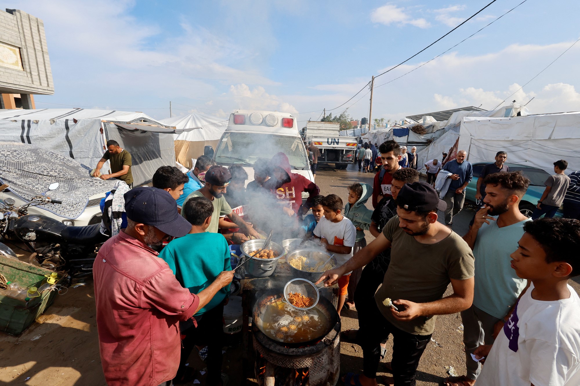 people cook together in an area full of tents