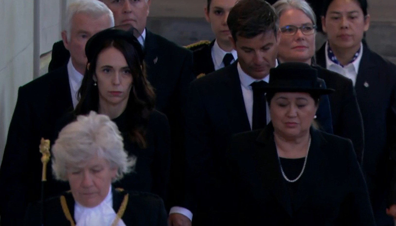 A woman dressed in all black walks in a crowd.