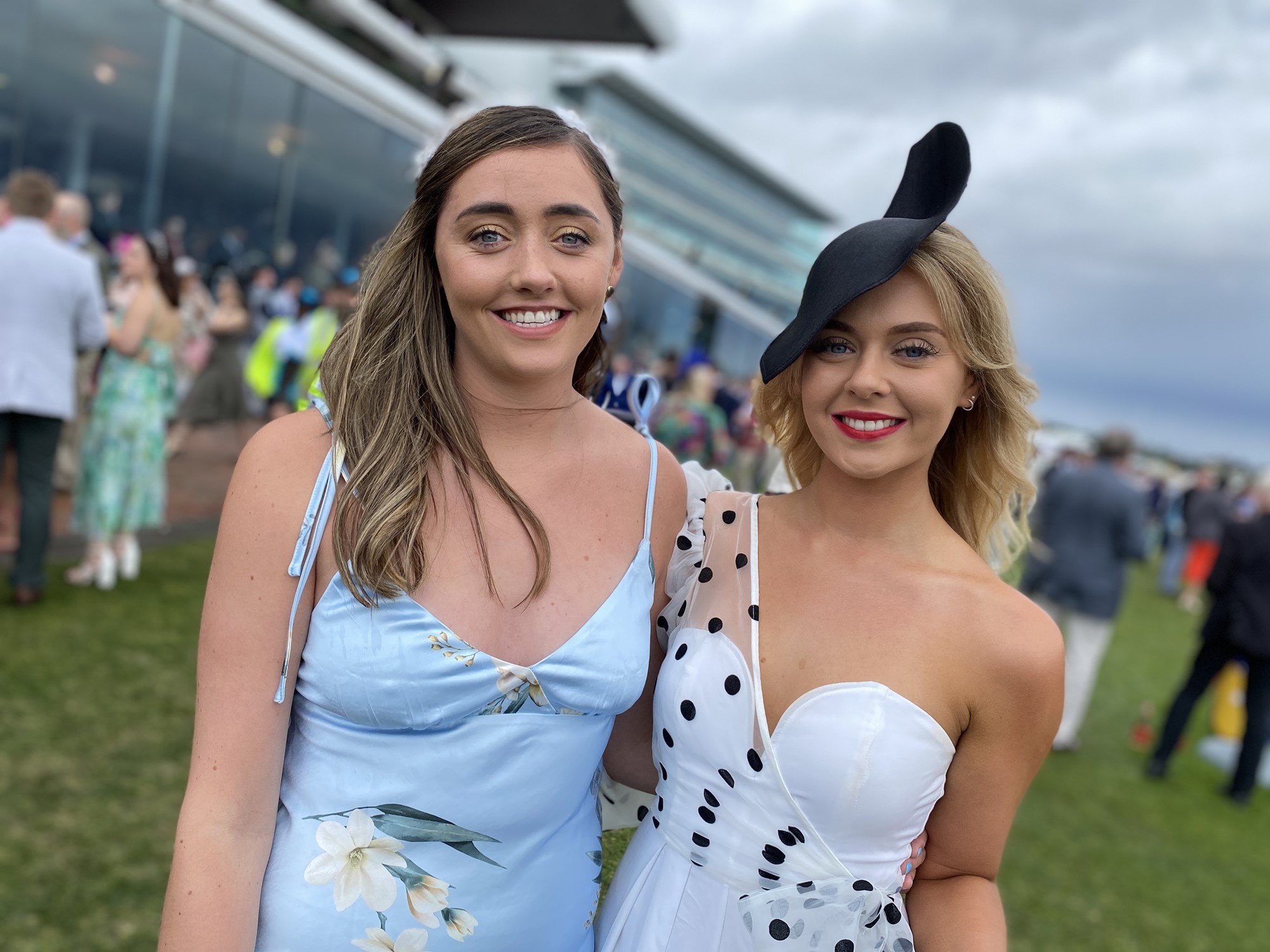 Two women smile, standing on a green oval.