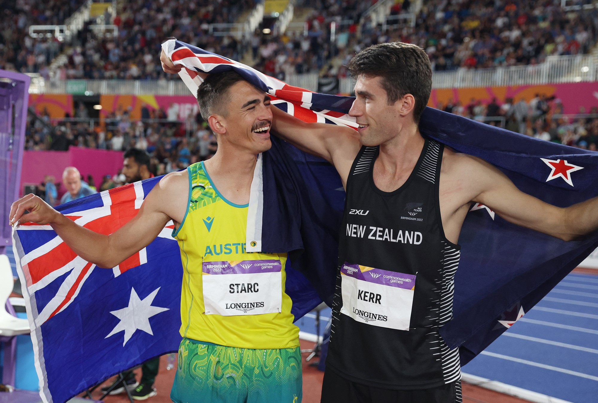 high jumpers brandon starc and hamish kerr smile at each other draped in flags