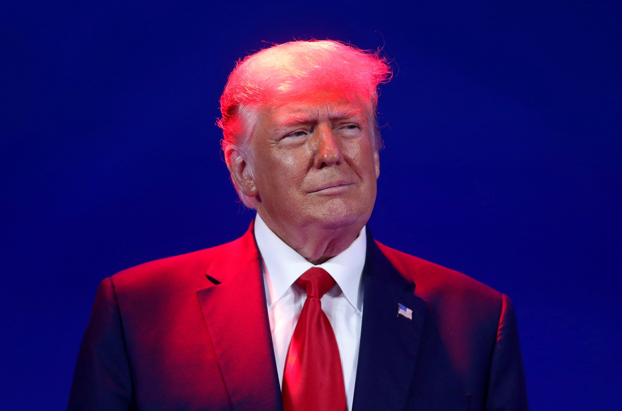 A photo of Trump smiling as he's bathed in a red light.