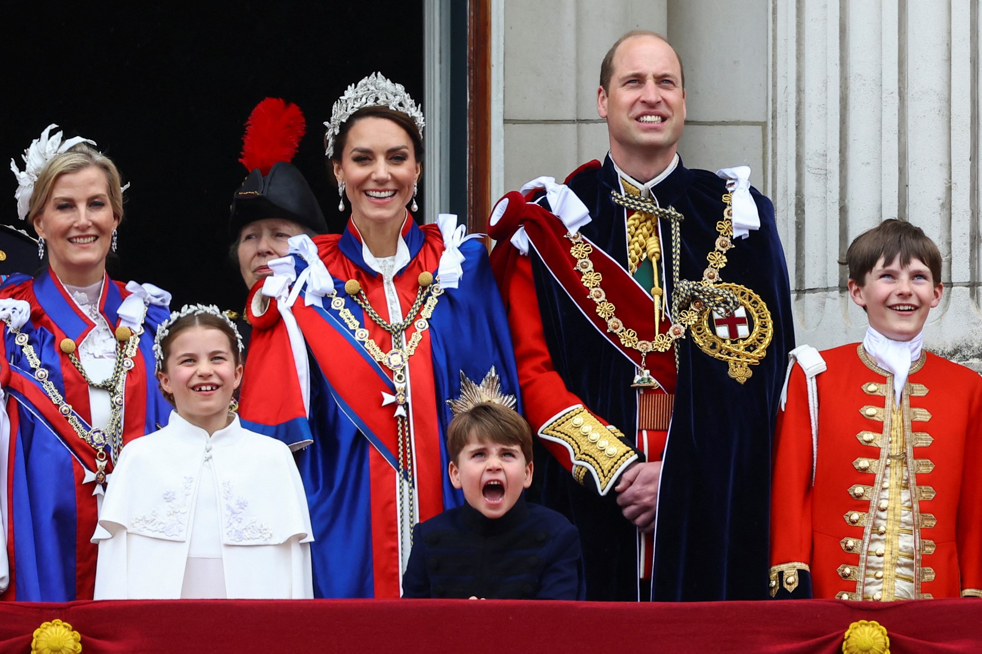 The royals smile on the balcony.