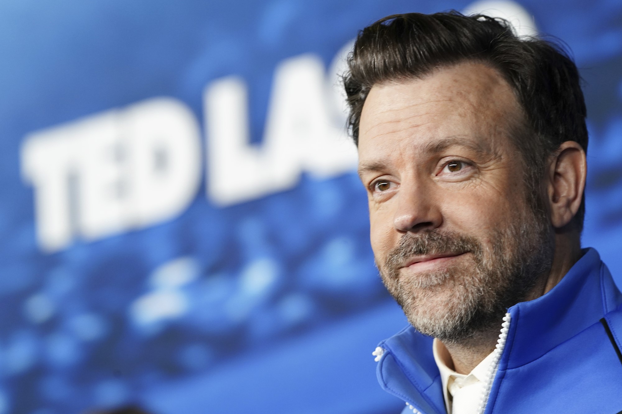 Jason Sudeikis in front of a Ted Lasso sign