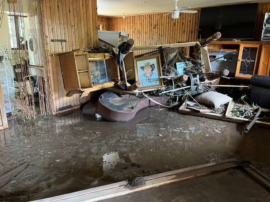 Photo shows the belongings of a home destroyed by flood waters with mud covering the flood.