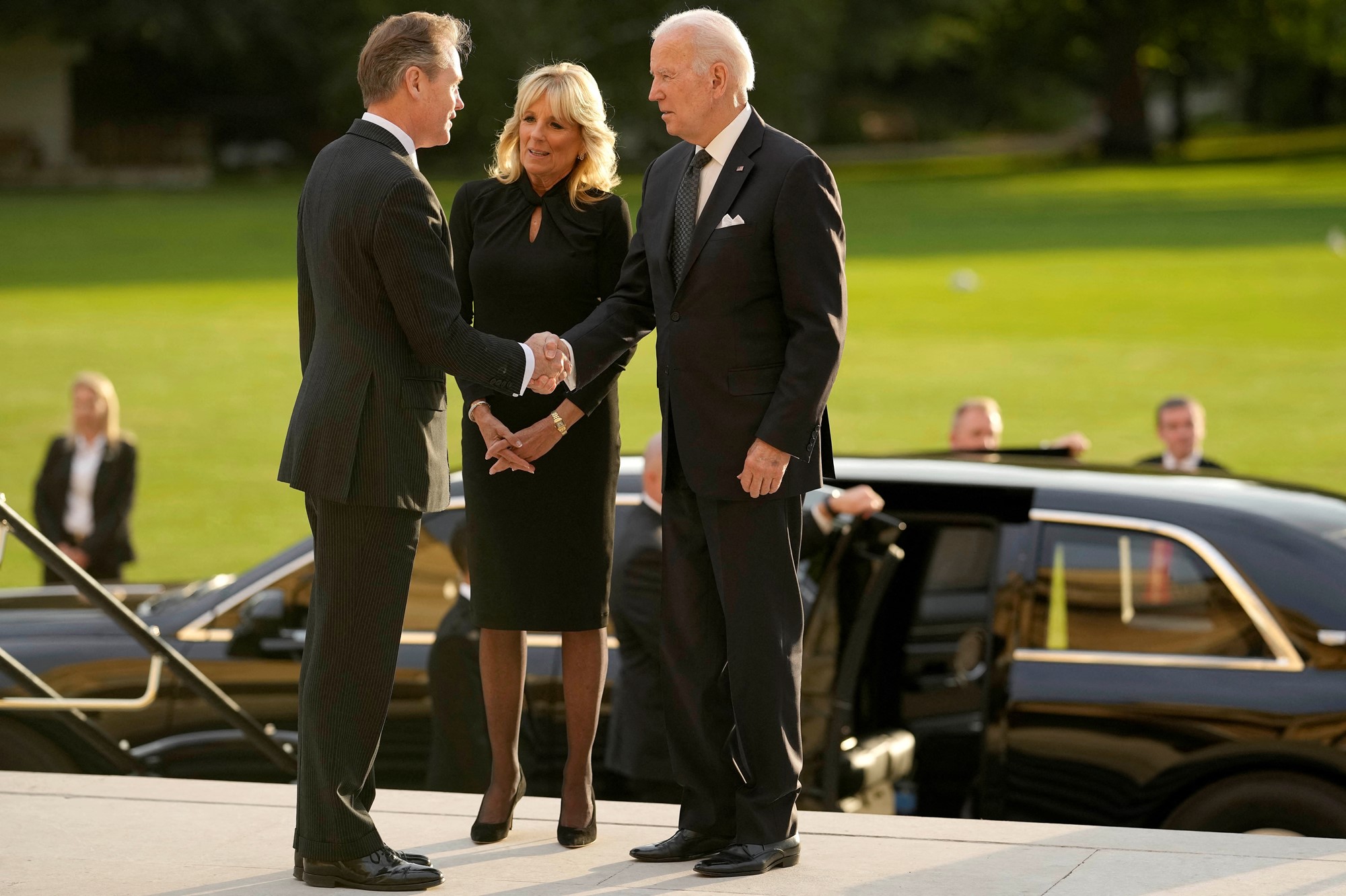 Joe Biden shakes hand with a man. Jill Biden stands by her husband's side