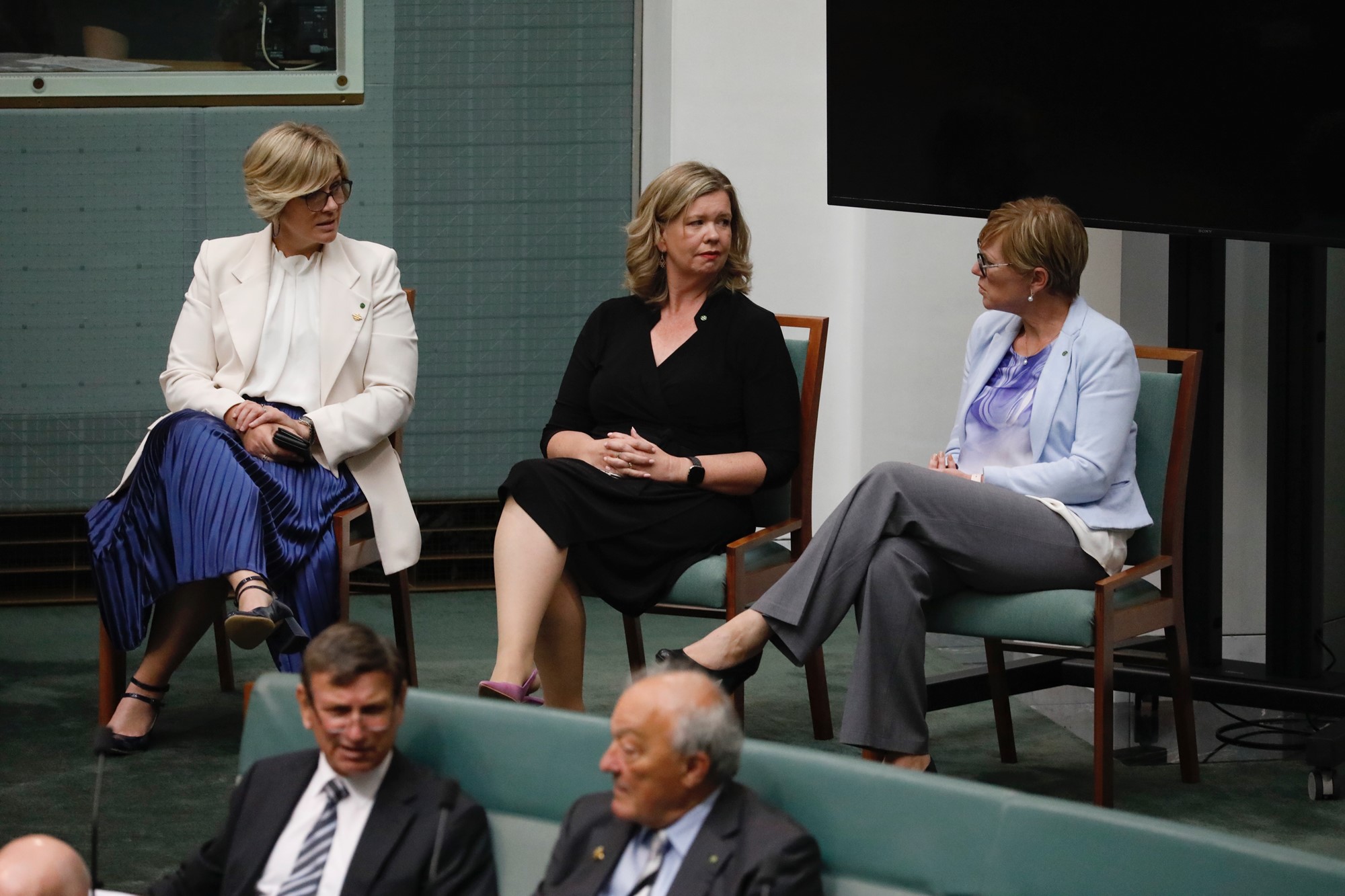Three female MPs sit together in parliament.