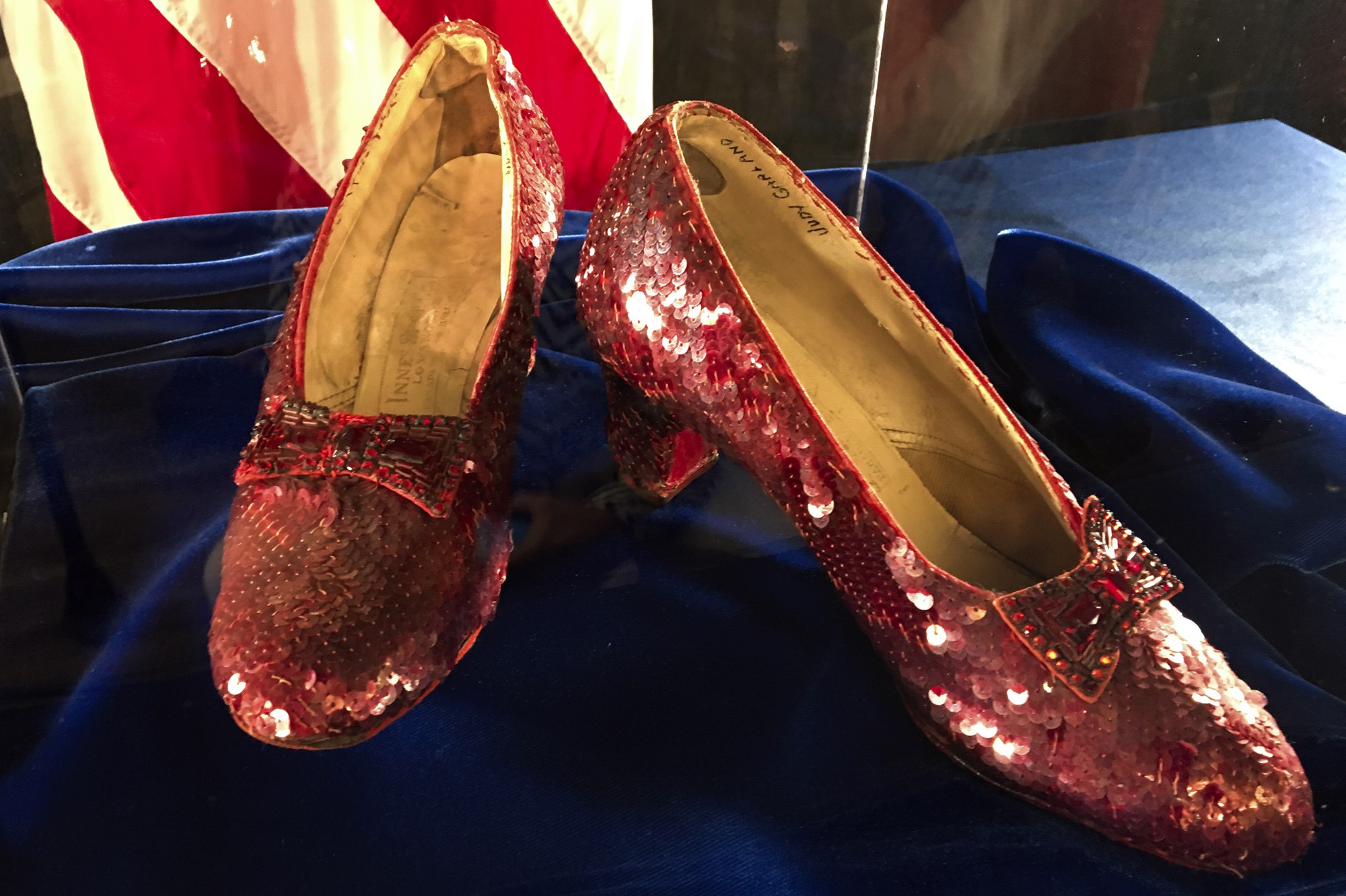 A close-up view of a pair of bright red, if old, ruby-encrusted shoes.