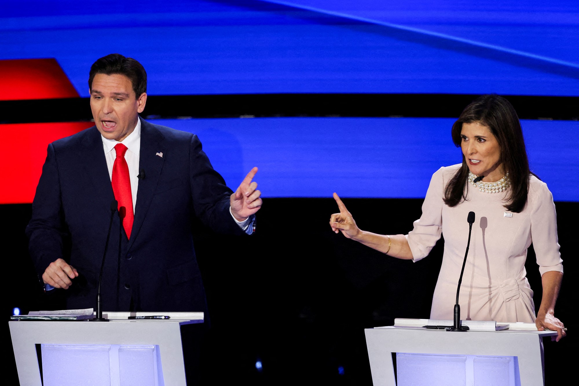 Ron DeSantis and Nikki Haley on stage arguing into microphones.