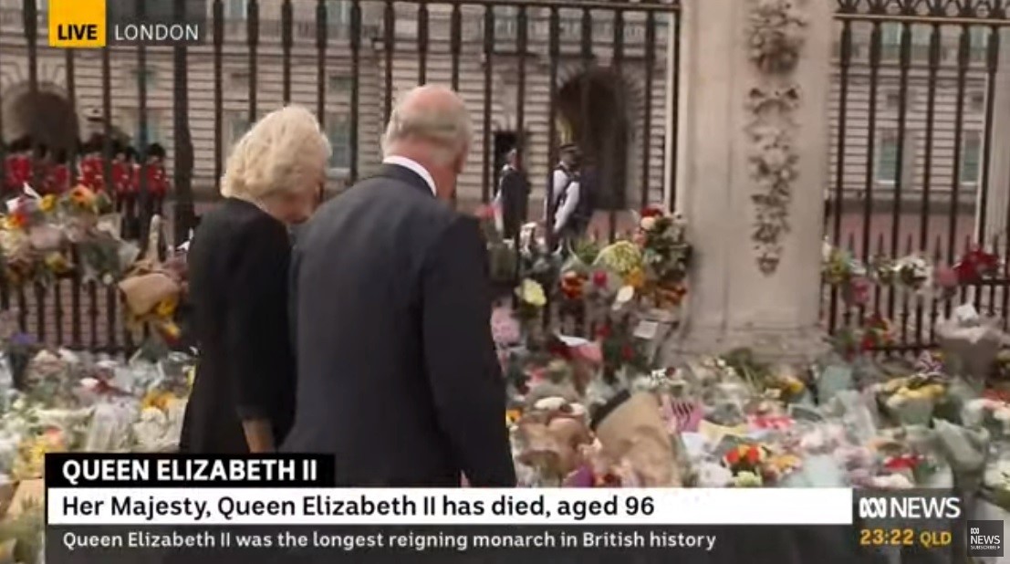 King charles III and his wife Camilla inspect floral tributes.
