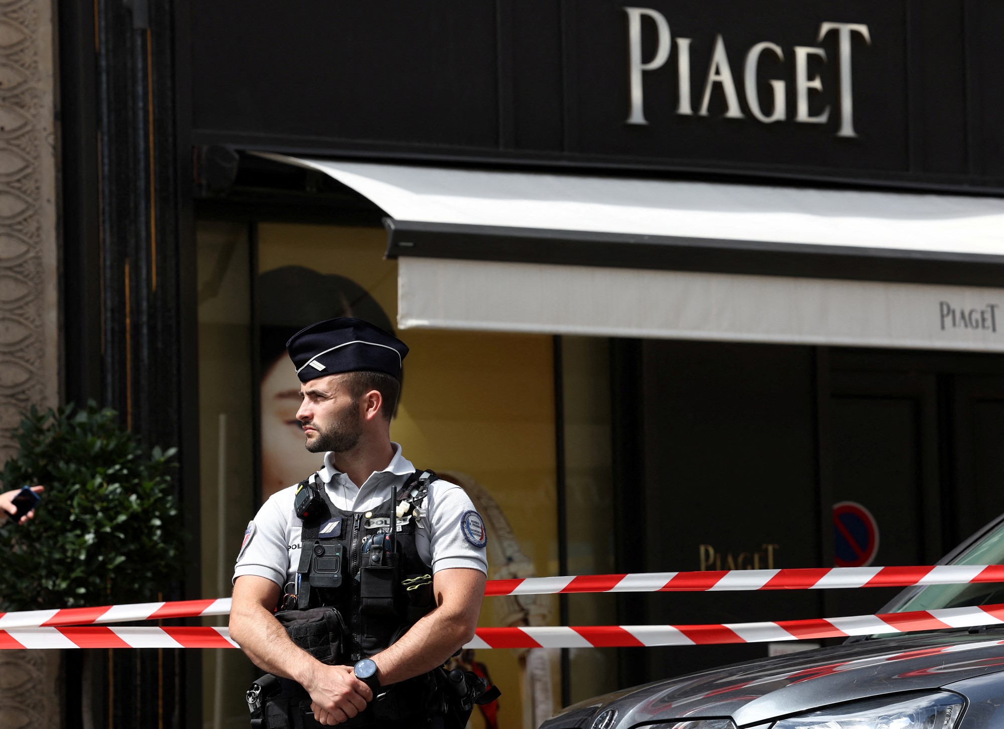 A man in police uniform stands guard outside the piaget store which is cordoned off by police tape