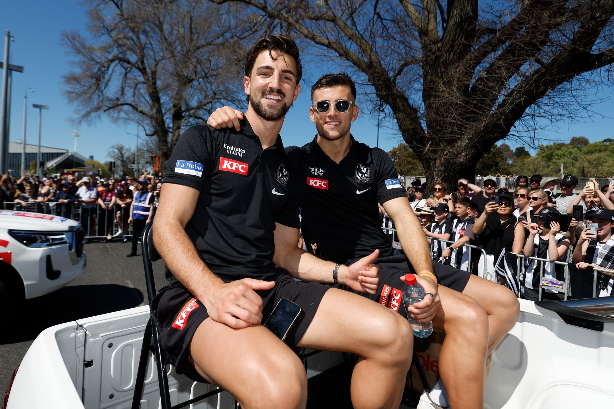 Josh and Nick smile for a photo while they sit on chairs on the back of a ute.