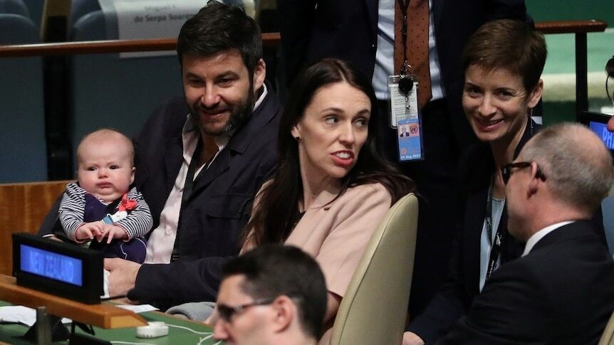 Jacinda and her husband sit with their little baby.