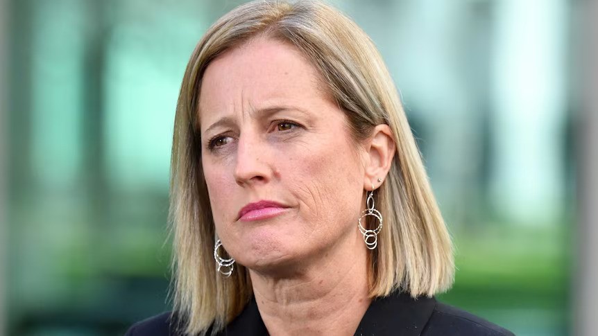 A close up of a white woman with shoulder-length hair and earrings