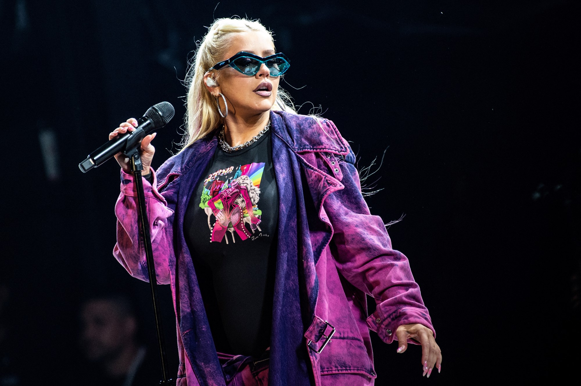 Christina Aguilera in a purple jacket holding a microphone